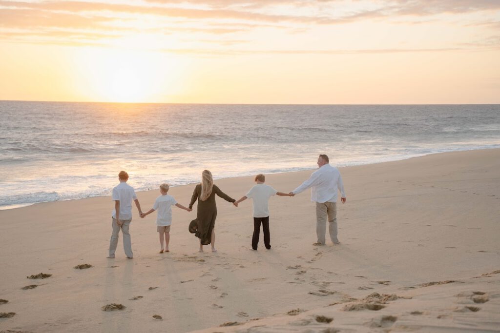 Family photo session in Los Cabos at sunset, walking together on the beach by the ocean.
