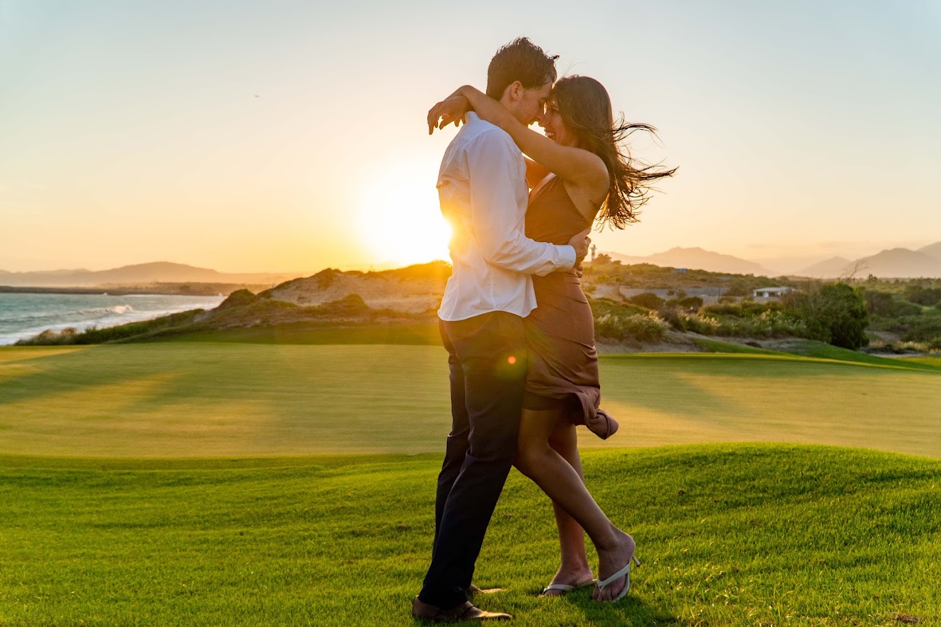 Romantic couple photo session in Los Cabos at sunset with ocean and golf course views.