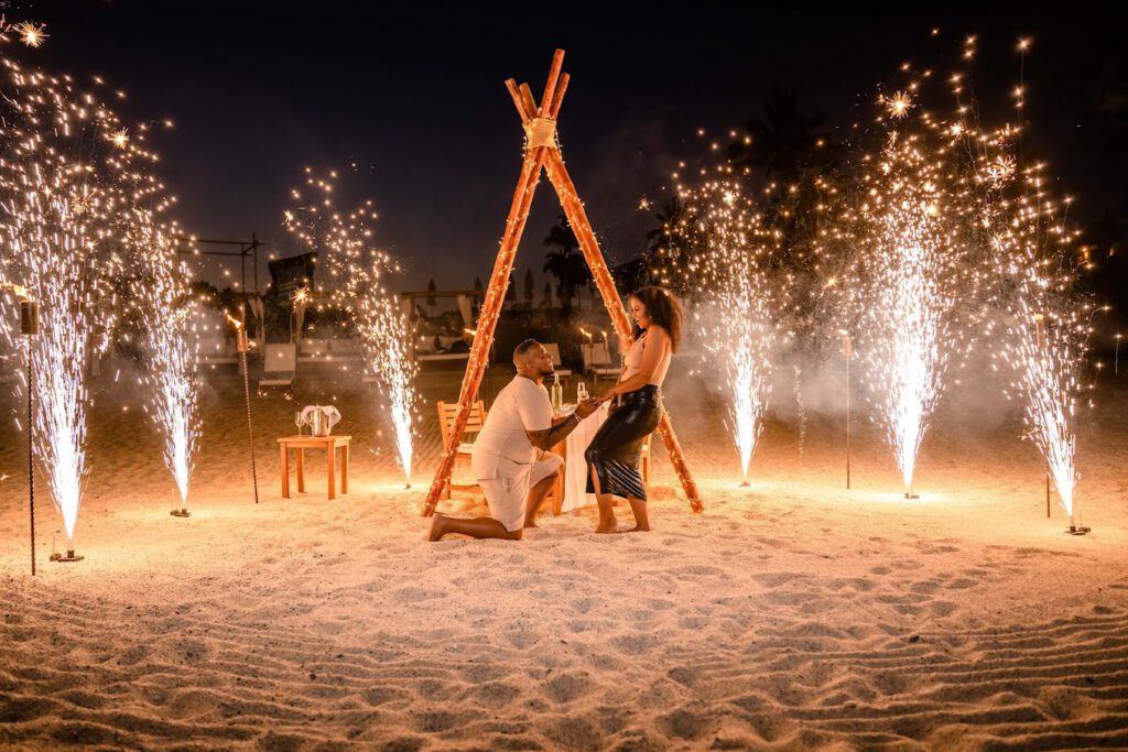 Marriage proposal in Cabo San Lucas with the groom kneeling and the bride surprised, surrounded by sparklers.